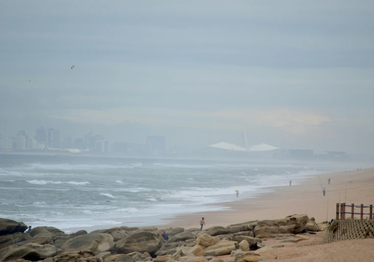 a long beach that has people walking on the shore