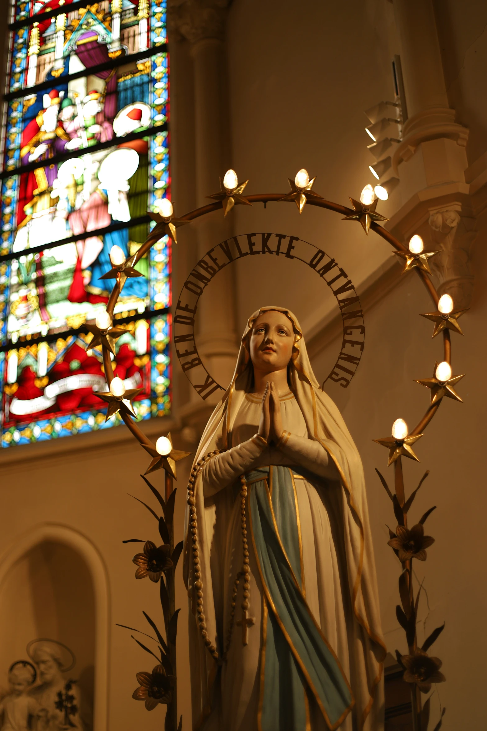 statue of mary in front of stained glass window