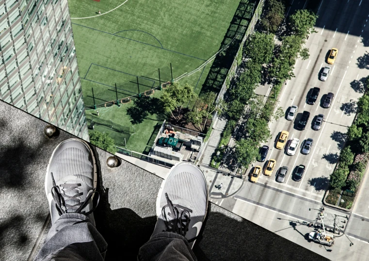 a person standing on top of a tall building looking over a parking lot