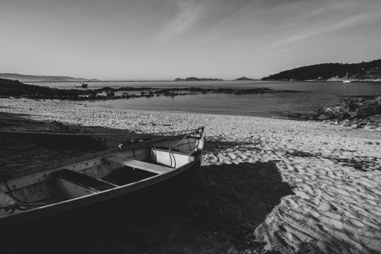 the boat sits on the sand beside the water