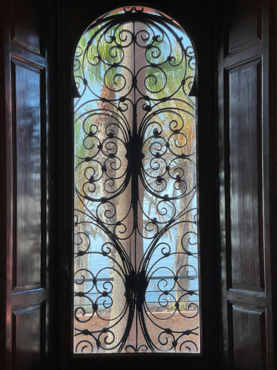 an open iron door in front of trees