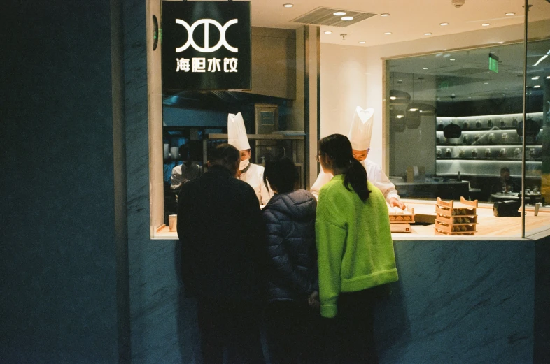 several people waiting in line to order from a bakery