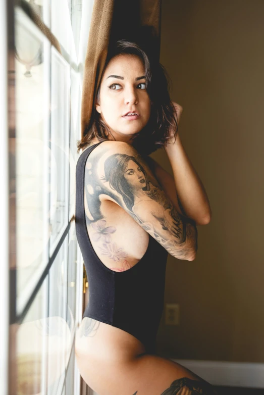 a woman with a tattoo and no panties, leaning on a window