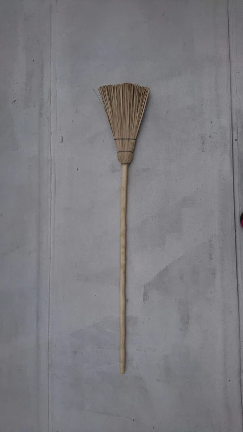 a straw broom against a wall with some paint