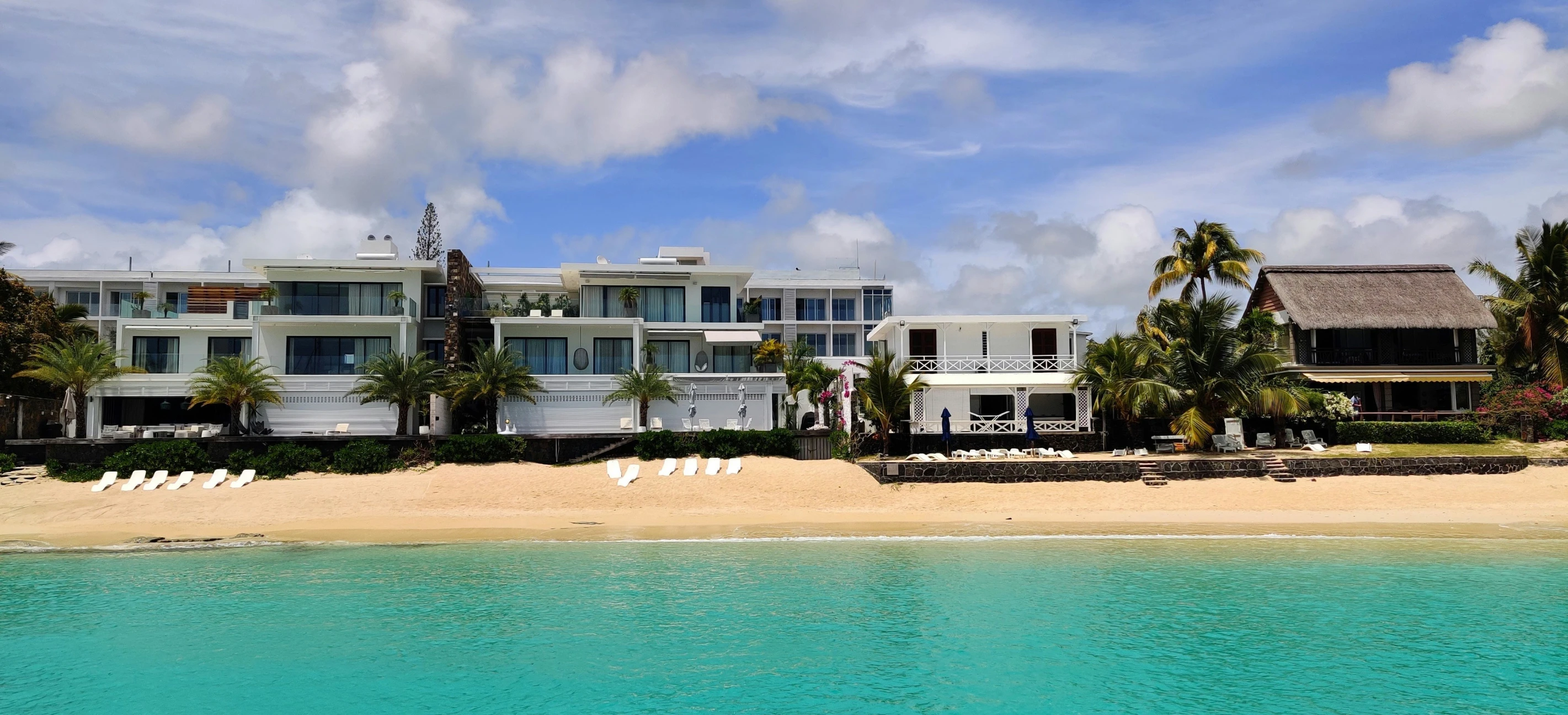 several white chairs line a beachfront in front of multi - story buildings