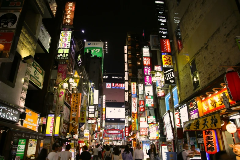 people are walking on an area that has neon signs on it