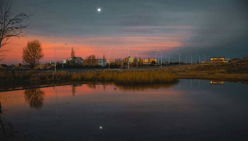 a reflection of a colorful sunset with buildings in the background