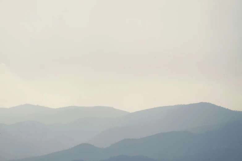 an airplane flies over the distant mountains and trees