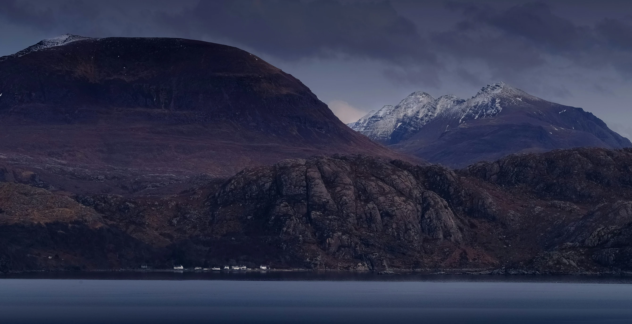 two tall mountains with a few white buildings on the side