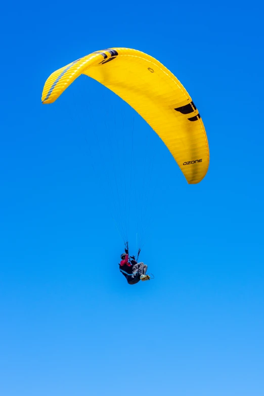 a big yellow wind sail with someone kitesurfing in the background