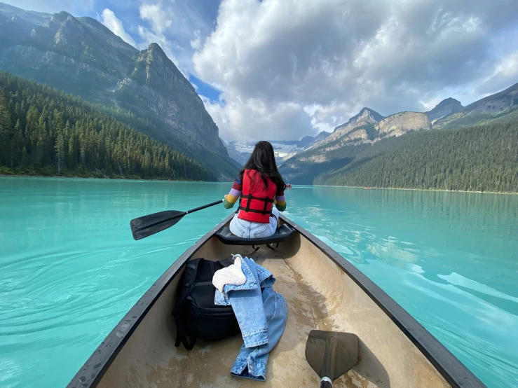 a woman paddling a canoe is down the river