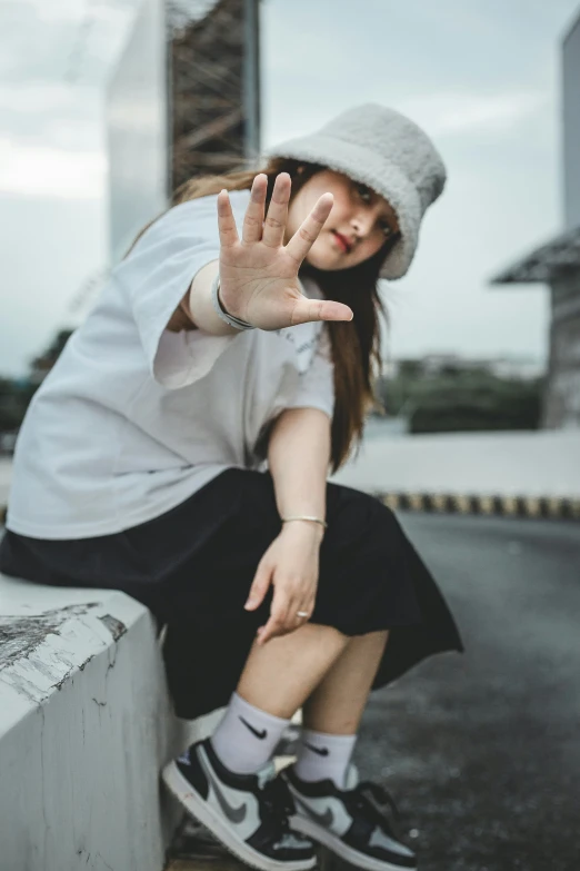 a woman sitting on top of a cement wall wearing black and white shoes