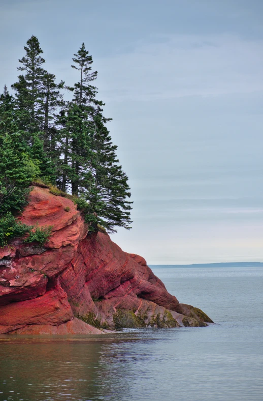 the shore of a body of water next to a red cliff