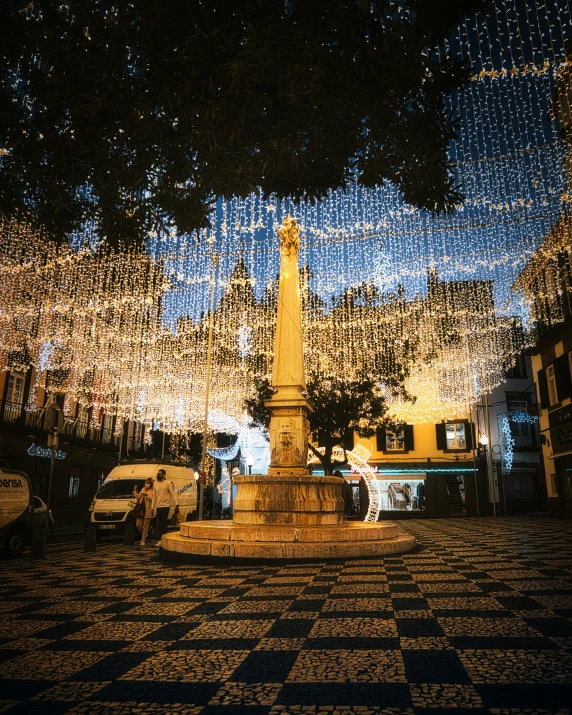 a sculpture surrounded by christmas lights in a street