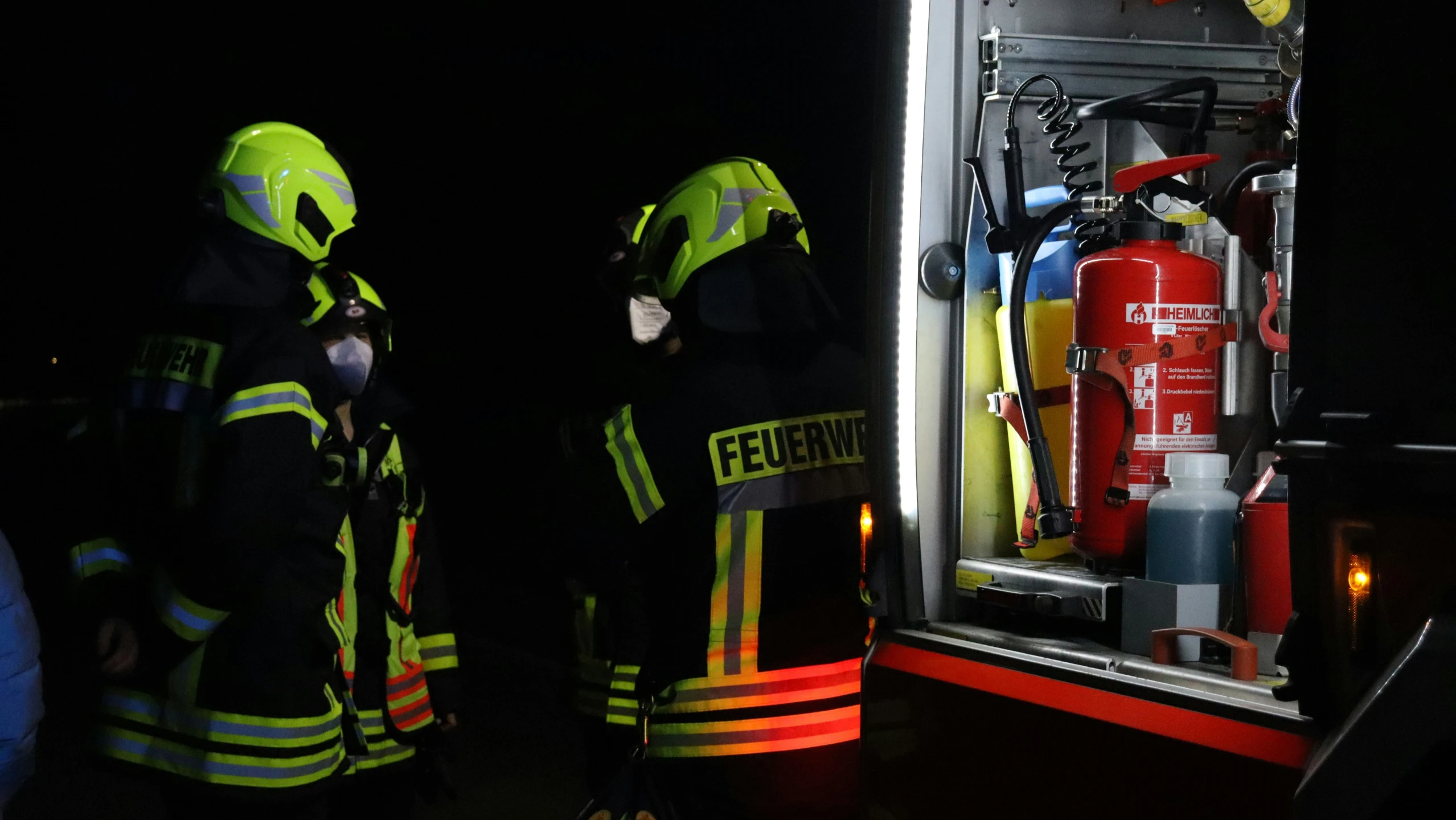 a couple of fire fighter standing near a red fire hydrant