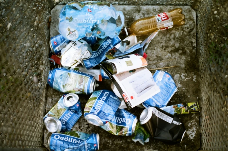 a pile of bottles and cans sitting on top of a cement block