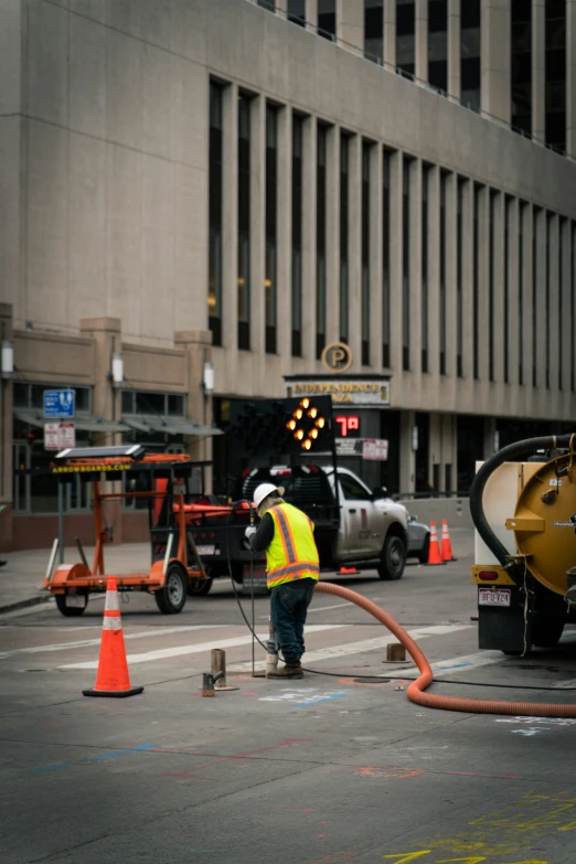 a street construction worker wearing an orange vest works on a road