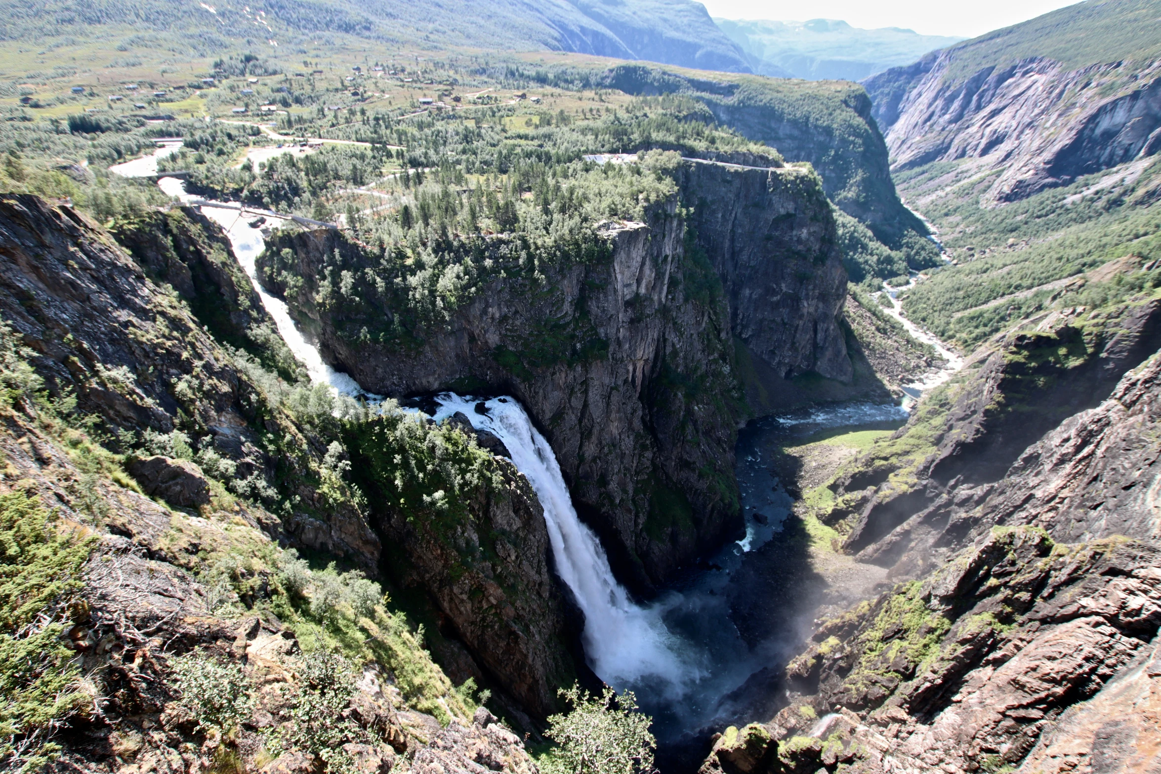 a large waterfall flowing over a canyon into a valley