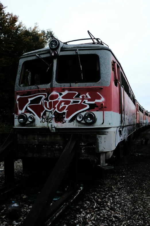a train is sitting on the tracks, covered in graffiti