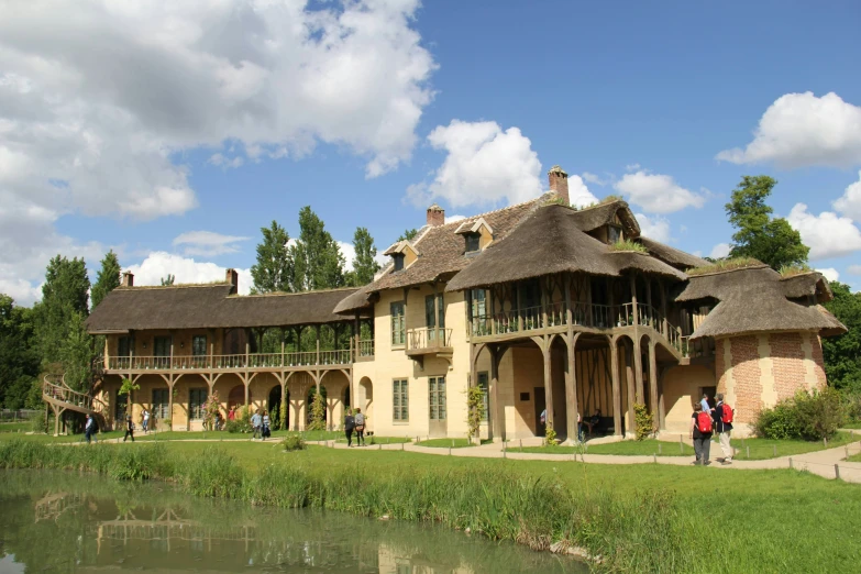 people are walking towards an old building with thatched roofs