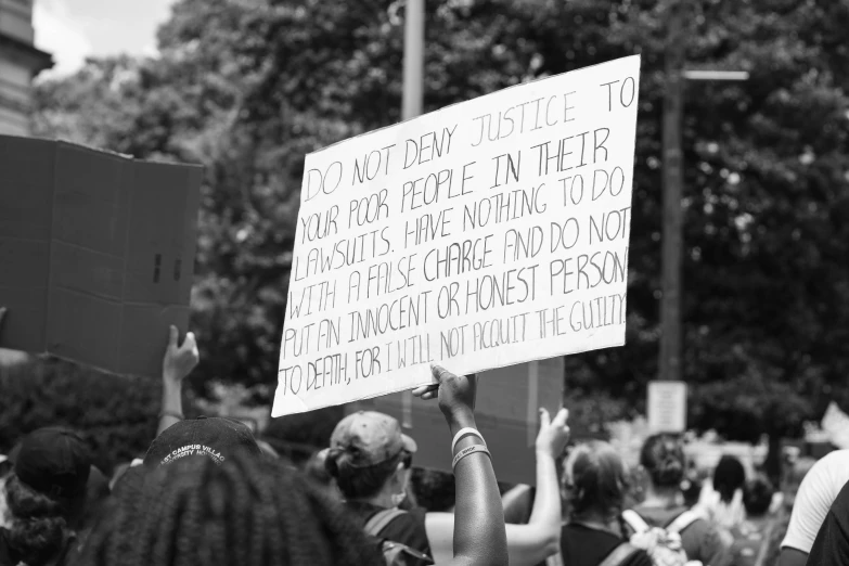 black and white pograph of person holding up sign reading to change people not to make sure