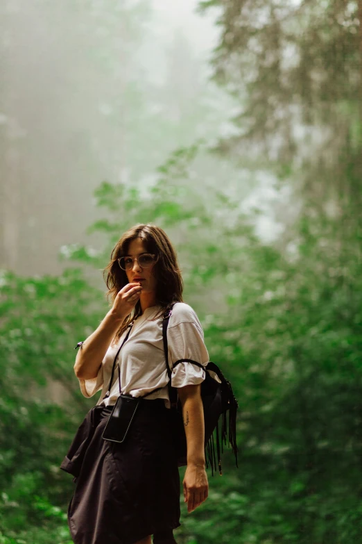 a woman in a dress is walking through a wooded area