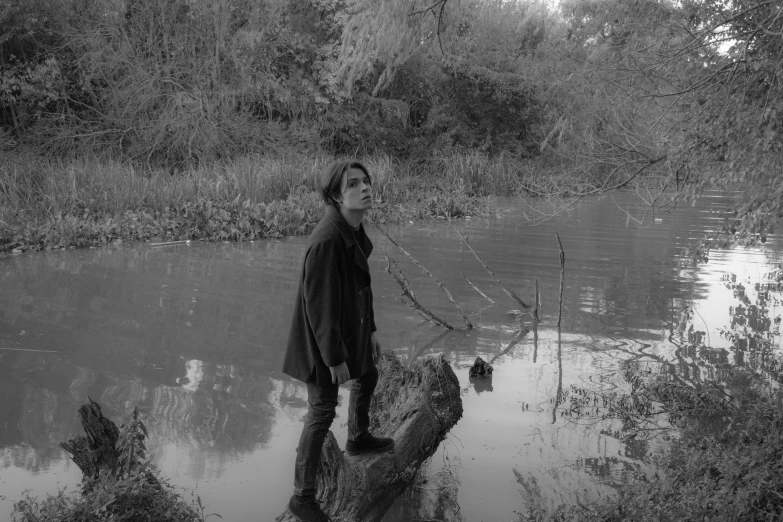 a woman standing in a river next to a log