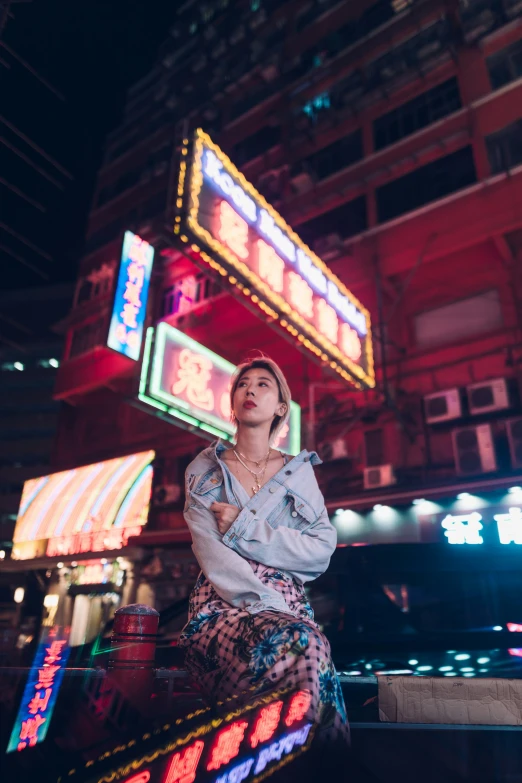 a woman standing outside of a large neon building at night