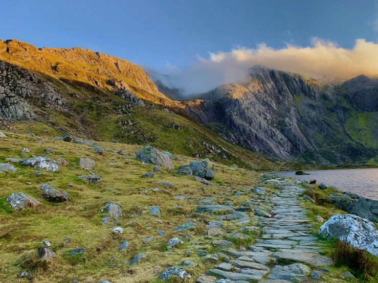 a pathway up a rocky mountain near a body of water