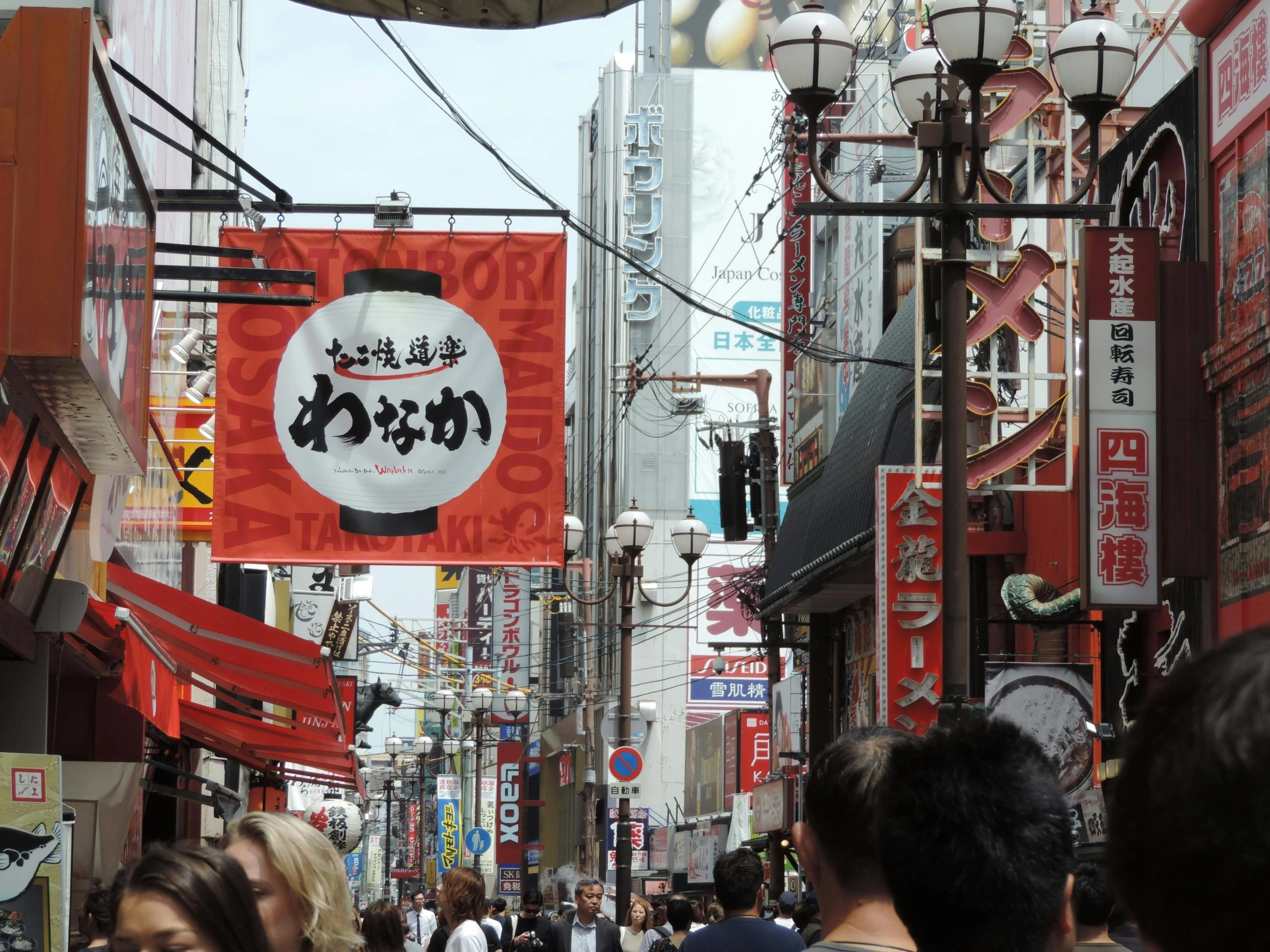 people walking down an oriental street near some signs