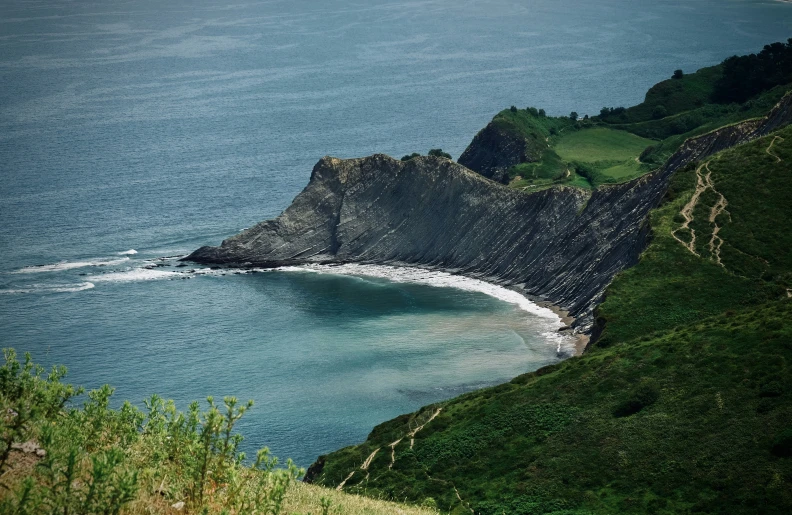 a large body of water surrounded by mountains and grass