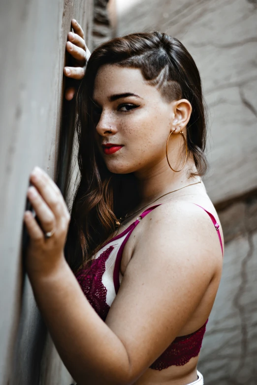 a woman standing in front of a wooden wall with her hand on the corner