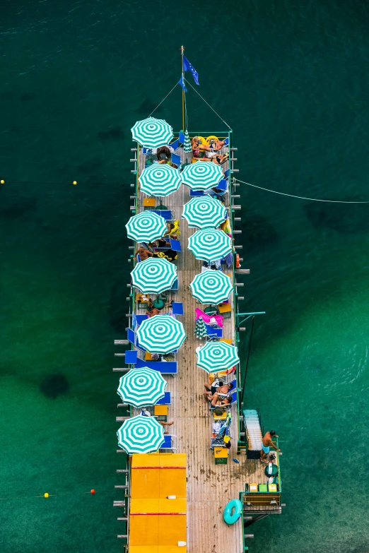 overhead view of a pier at sea with many umbrellas