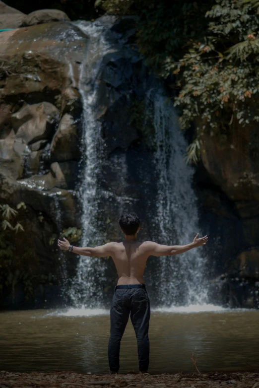 a man standing in front of a waterfall in the jungle