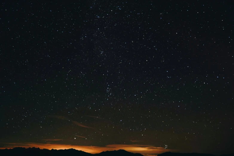 a night sky with stars above a large mountain