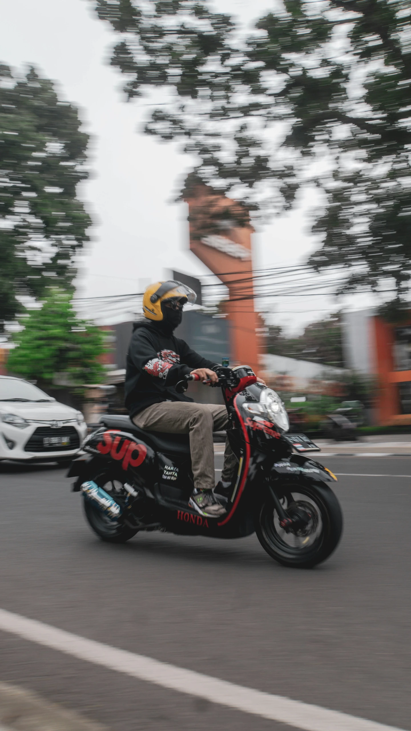 a motorcyclist rides on a road with trees in the background