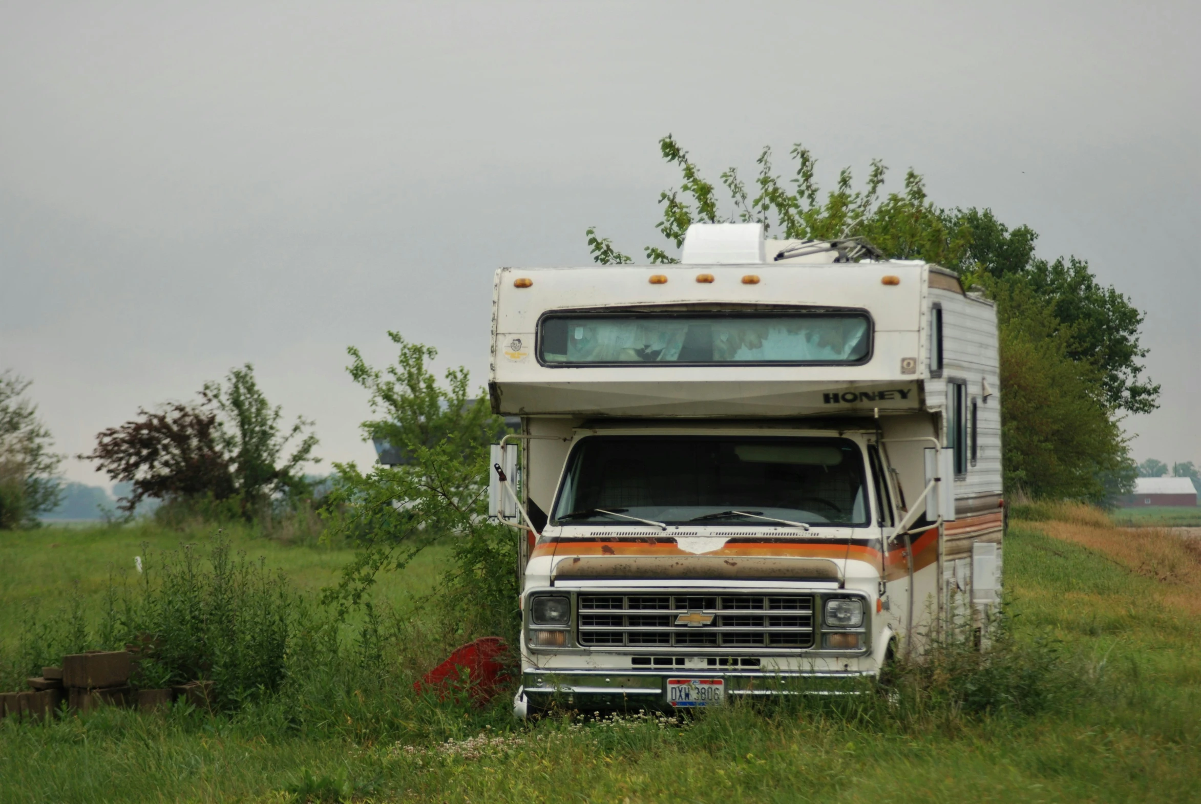 an old dump truck sits out on the grassy lot