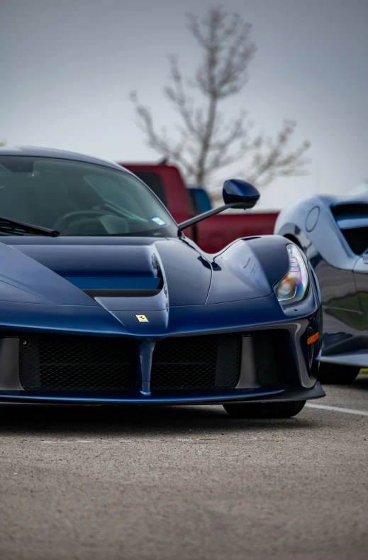 a black and blue sports car on asphalt in front of red cars