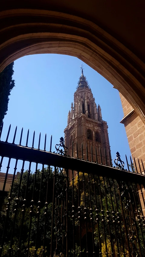 the cathedral spire towers behind a black metal fence