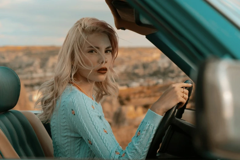 a young blond woman holding her seat on a green car