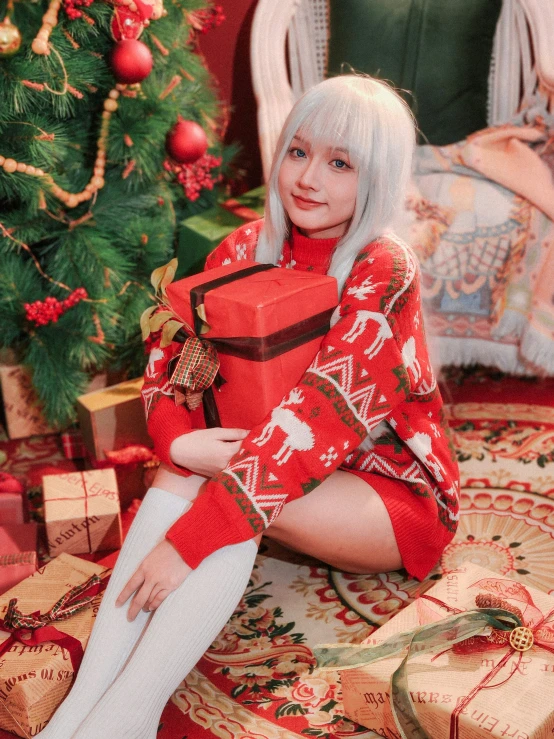 a woman sitting with a christmas present on the floor