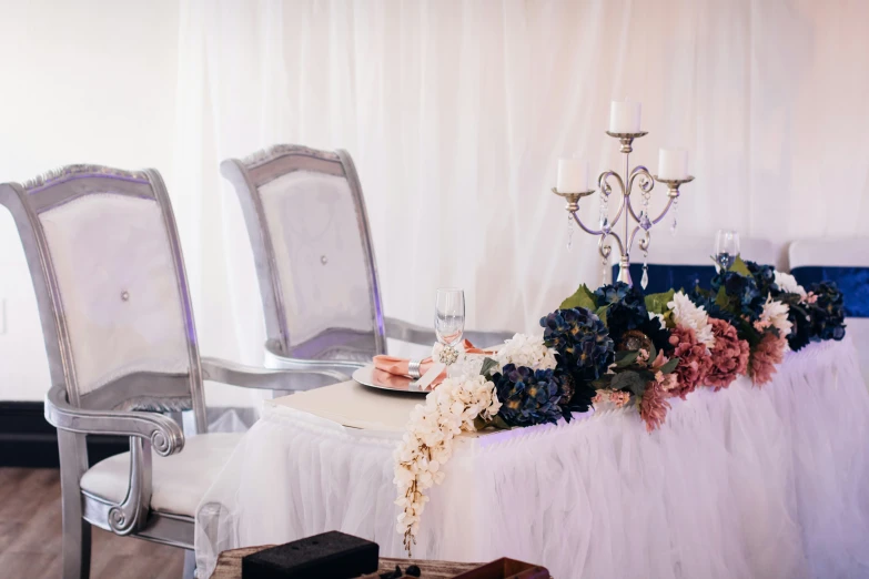 the table has two white chairs with flowers on it