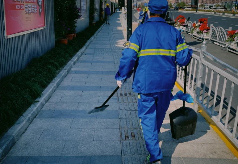a man in a blue work suit walking down the street