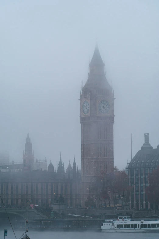a city is covered in fog and has a tall clock tower