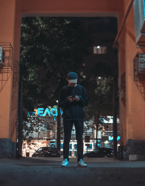 a man stands outside while looking at his cellphone