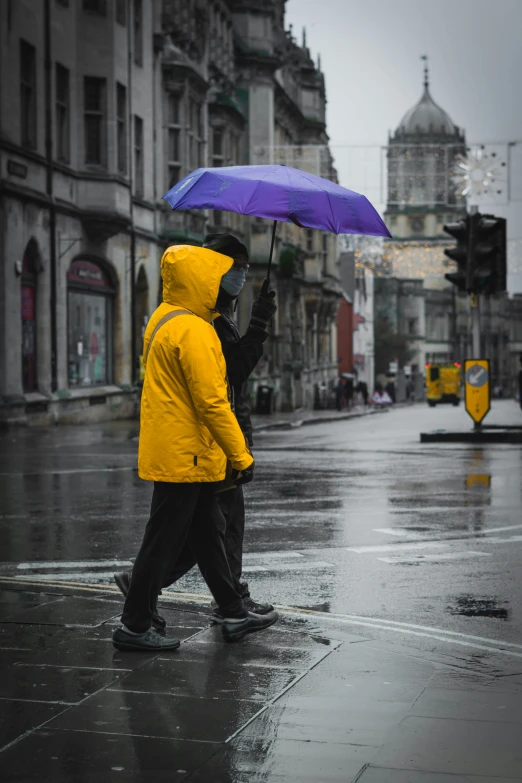 the two people in coats are walking down the street with umbrellas