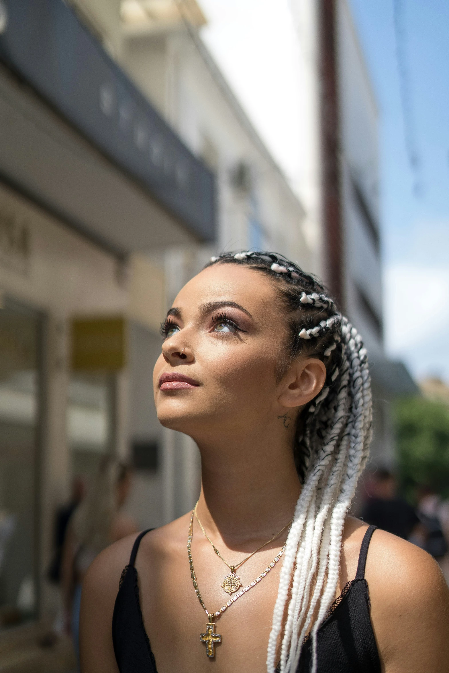 a woman with long hair with cornrows looking up in a crowd