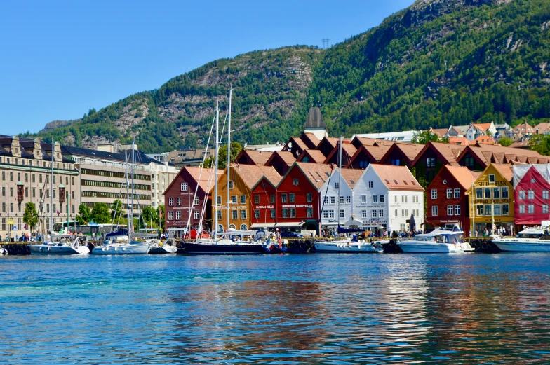 several buildings and boats near the dock with a mountain in the background