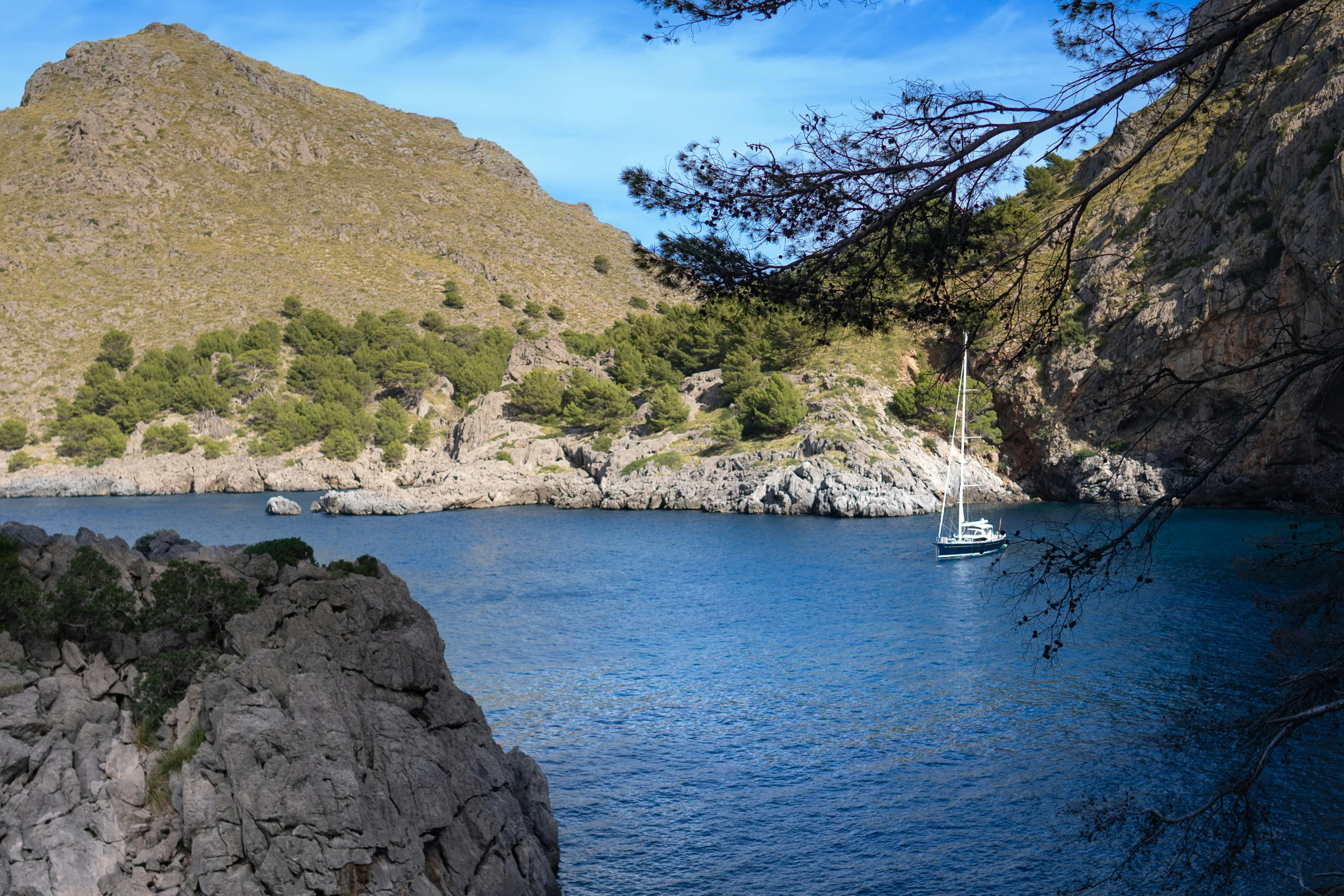 a sailboat floating in a lake with a mountain behind it