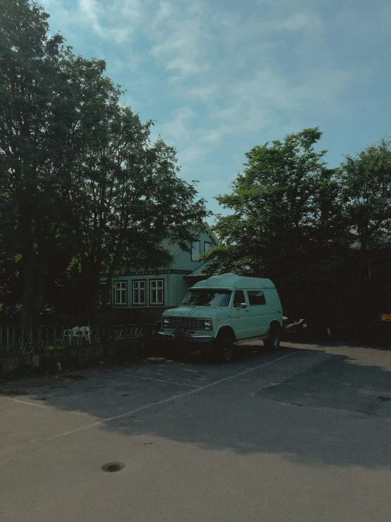 a green van is parked in a driveway near a fence